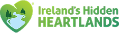 Logo for Ireland’s Hidden Heartlands featuring a green heart with a winding river and trees, beside the text Irelands Hidden Heartlands in bold green letters—perfect inspiration for Greenway Lane Art Studio creations.